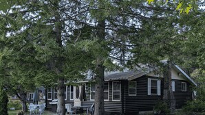 Une cabane en rondins dotée d’un coin repas et d’un espace extérieur aménagé pour s’asseoir.