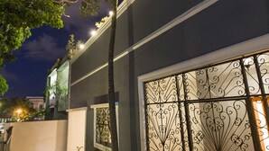 Un edificio moderno con facciata scura, cancelli in metallo decorativi e un vialetto che conduce all'ingresso.