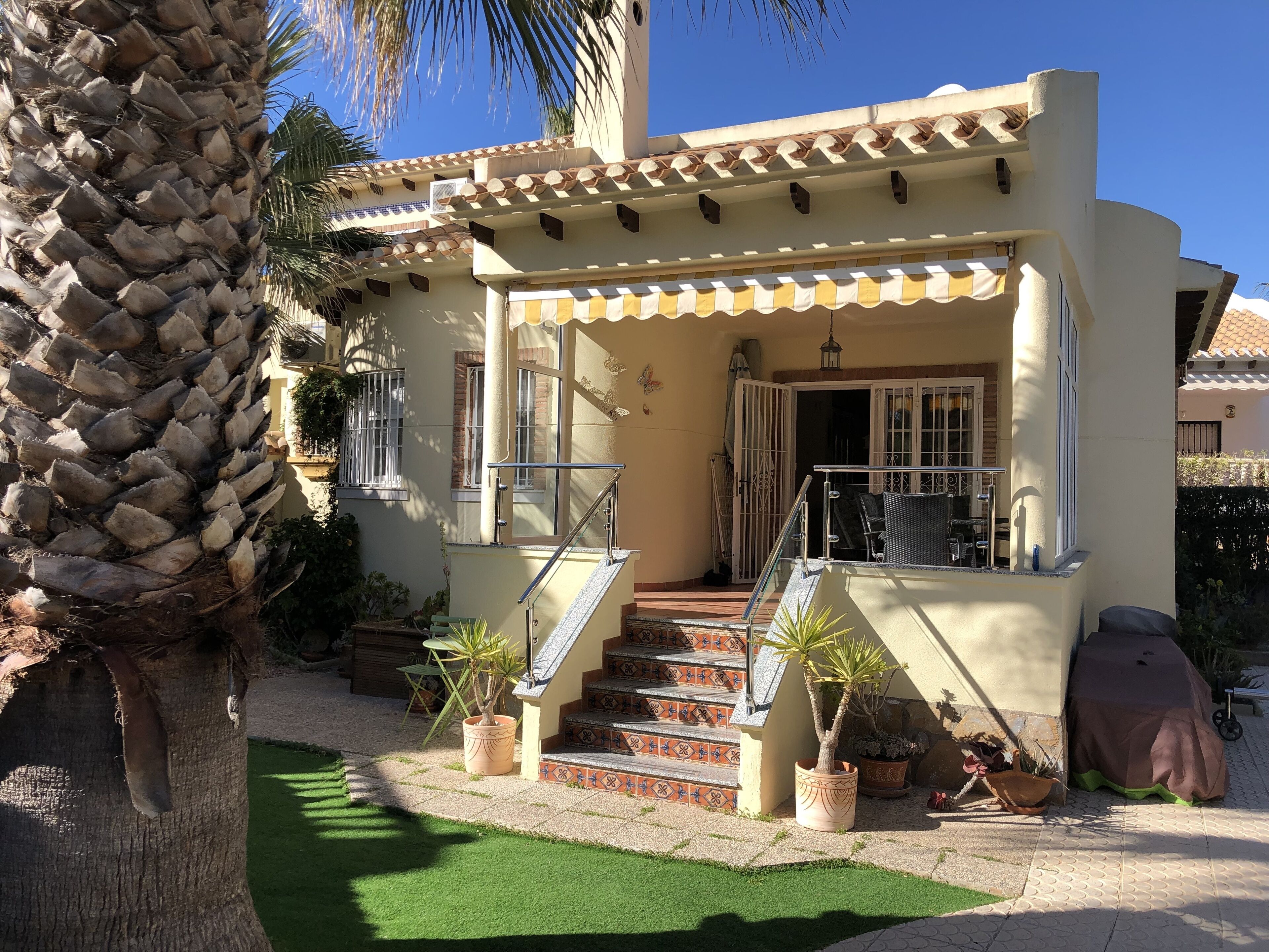 A two-story house with a balcony, a staircase, and a palm tree.