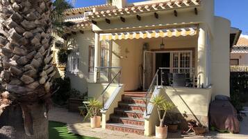 A two-story house with a balcony, a staircase, and a palm tree.