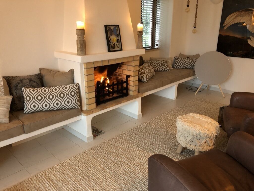 A living room with a fireplace, a sofa set, patterned cushions, and a round side table.