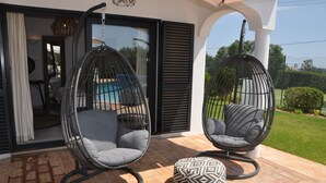 Un patio con due poltrone nere a forma di uovo e un poggiapiedi decorato.