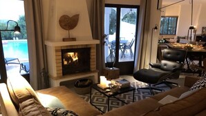 Un soggiorno con camino, un divano, un tavolino da caffè e vista su un patio esterno.