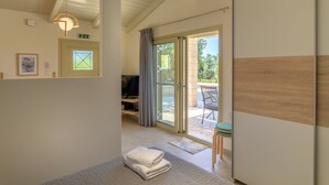 Camera d'albergo con un letto, una TV, una porta scorrevole in vetro che dà su un balcone e una piccola zona salotto.