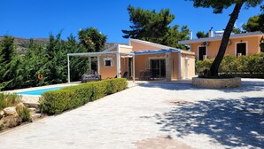 Una villa moderna con piscina, area salotto esterna e portico coperto.