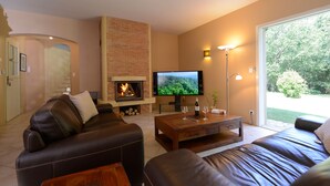 A living room with a fireplace, leather sofas, a coffee table, and a TV.