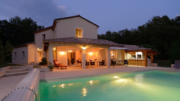A two-story house with a swimming pool, outdoor seating area, and a covered patio.