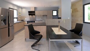 A modern kitchen with stainless steel appliances, a granite countertop, and black chairs.