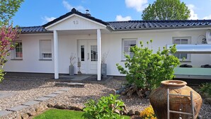 A white house with a number 13 on the front door, a garden with a large pot and a ladder, and a clear blue sky. - House, superior equipment, city limits Rostock, pets welcome, internet (Groß Kussewitz)
