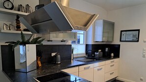 A modern kitchen with a black marble countertop, stainless steel appliances, and white cabinetry. - House, superior equipment, city limits Rostock, pets welcome, internet (Groß Kussewitz)