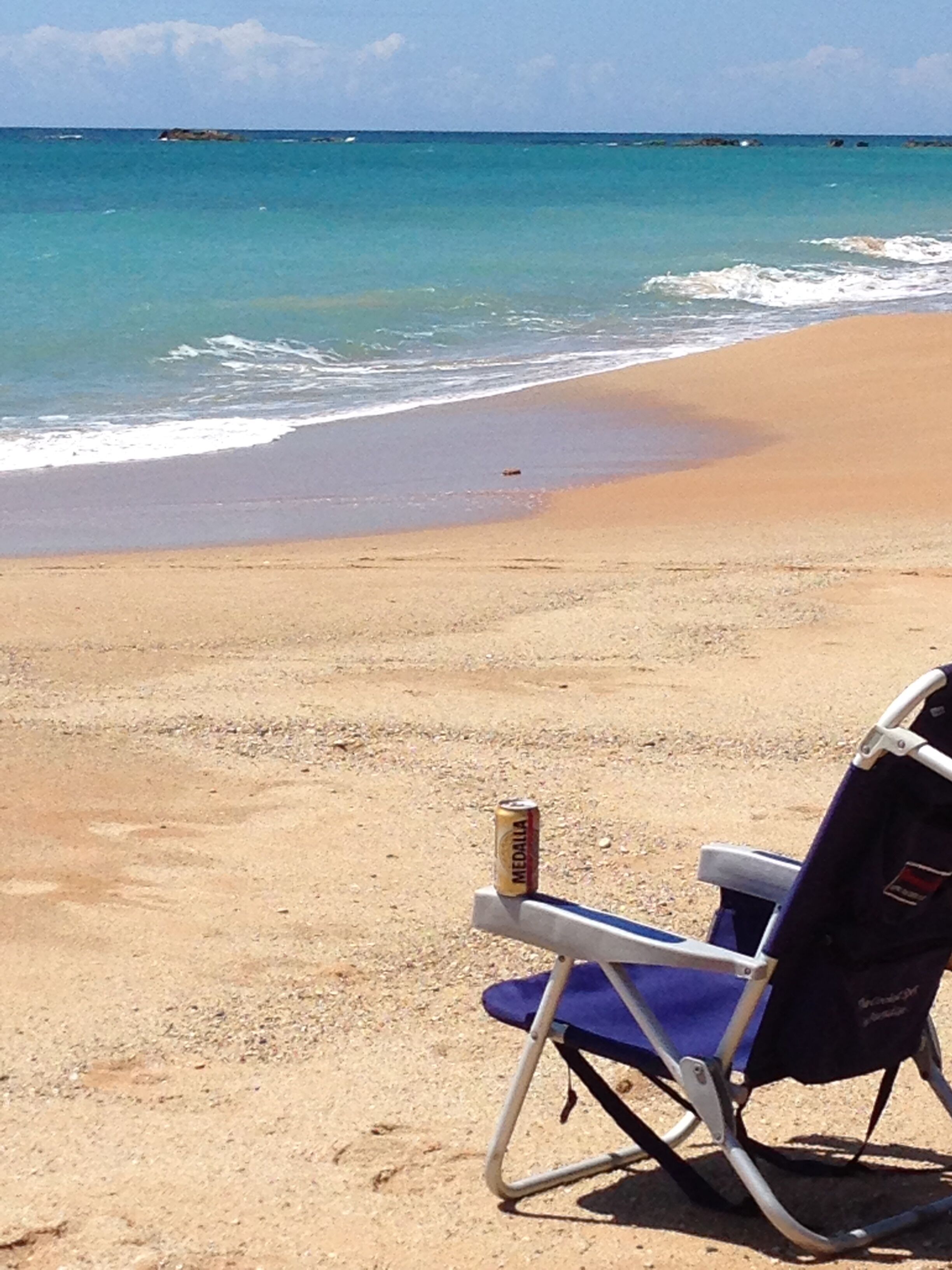 A beach with a chair and a can of beer.