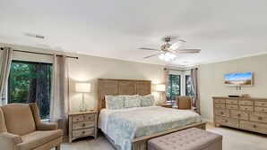 A bedroom with a large bed, two nightstands, a chair, a bench, a dresser, and a ceiling fan. - SeaPines, Ranch style home, Nicely updated, Great outdoor space, Pet friendly (hilton head)