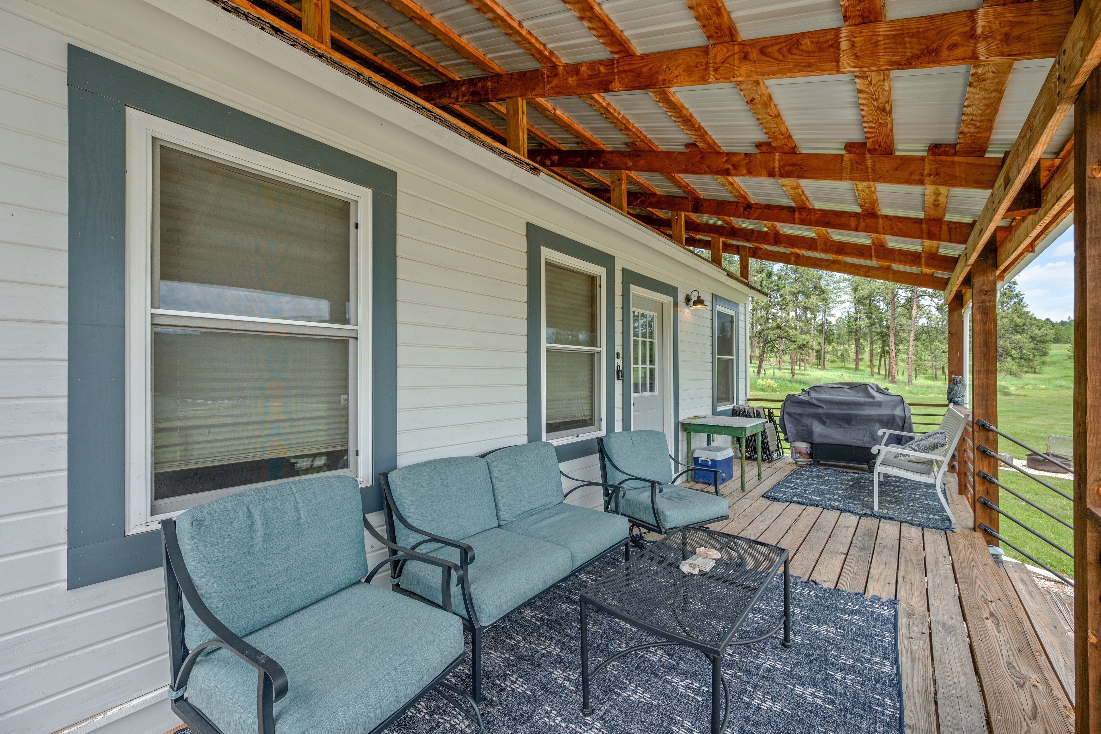 Eine überdachte Veranda mit einer Couch, Stühlen und einem Tisch.