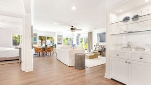 A spacious living area with a dining set, a sofa, and a kitchen area with glass shelves. - 63 South Sea Pines: A BESTNEST by Beverly Serral (Hilton Head Island)