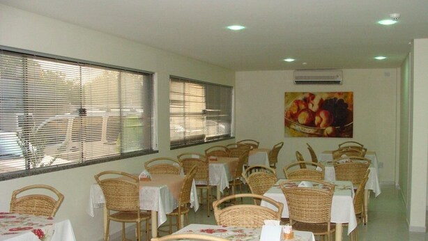 Un espace repas avec des chaises et des tables en osier, chacune étant recouverte d’une nappe blanche.