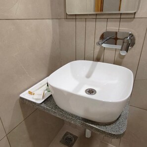 A bathroom with a white sink, a towel rack, and a small trash bin.