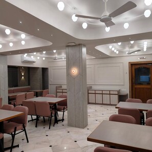 A restaurant interior with tables, chairs, ceiling fans, and recessed lighting.