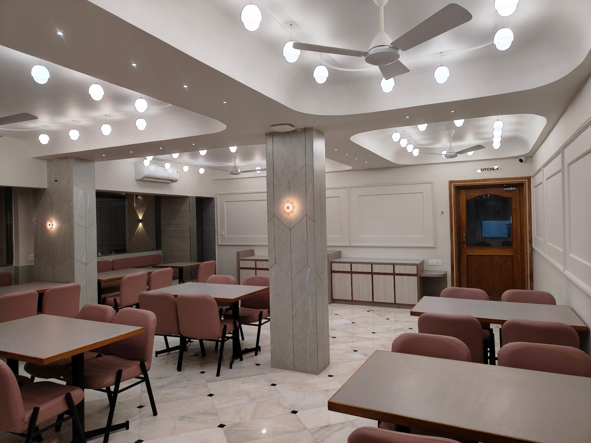 A modern restaurant interior with round tables, chairs, and a ceiling fan.