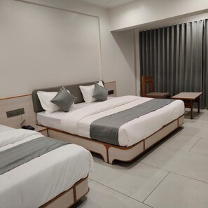 A hotel room with two beds, a bedside table, a chair, and a curtain.