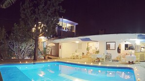 A swimming pool with a deck area, surrounded by a building with a covered patio and outdoor seating. - Hotel Teocalli (Tepoztlán)
