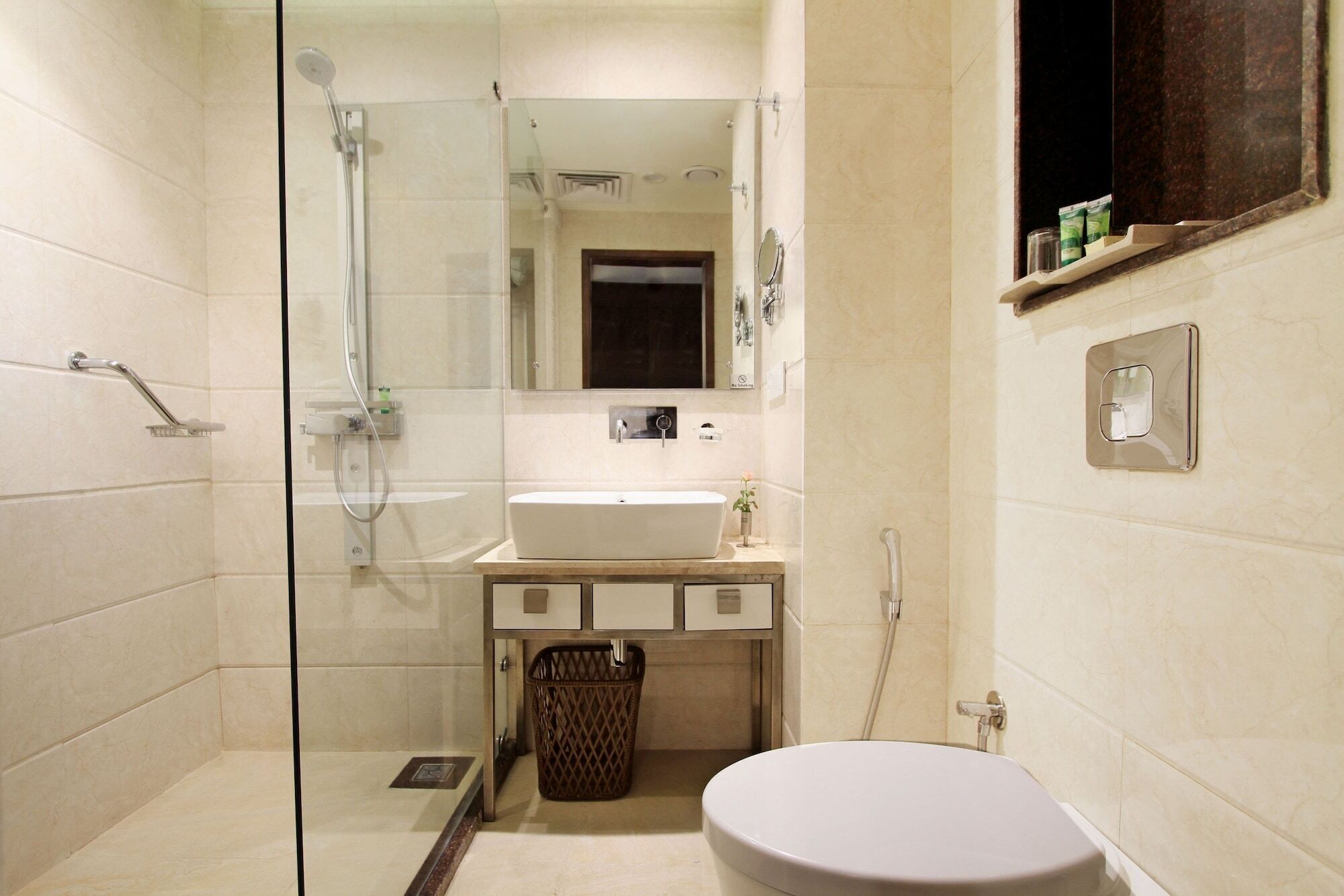 A modern bathroom with a glass-enclosed shower, a sink with a mirror above it, and a toilet.
