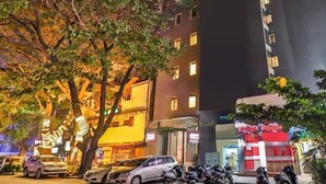 Un edificio de varios pisos con ventanas iluminadas y un árbol en la fachada.