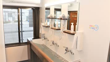 Une salle de bain avec un grand lavabo, plusieurs miroirs et des sèche-cheveux.