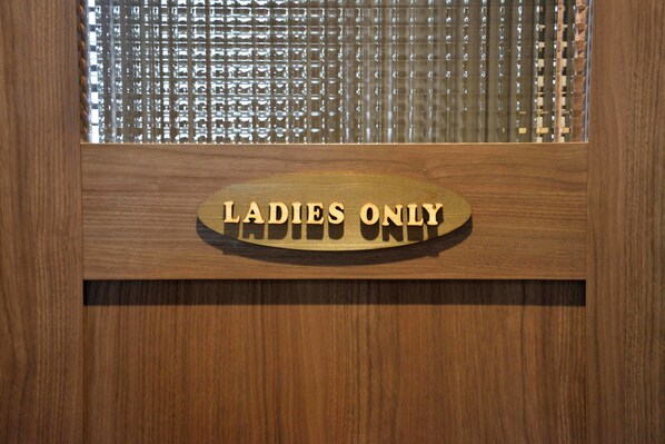 A wooden sign with the text "LADIES ONLY" on a hotel reception desk.