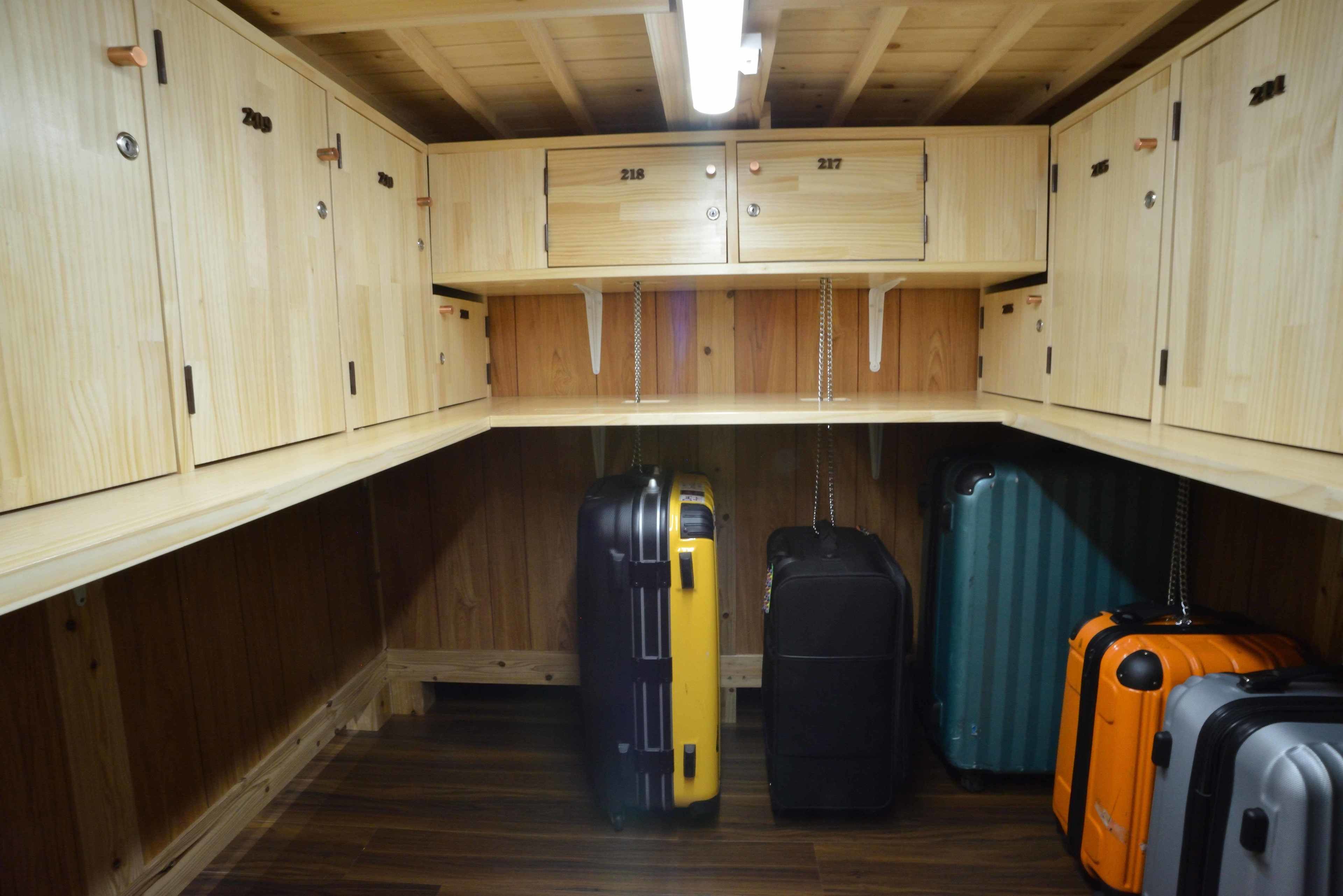 A corner of a room with wooden lockers numbered 218 and 217, and several suitcases of various colors.