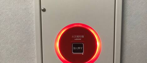 Un détecteur de fumée doté d’un voyant rouge et d’indications en japonais.