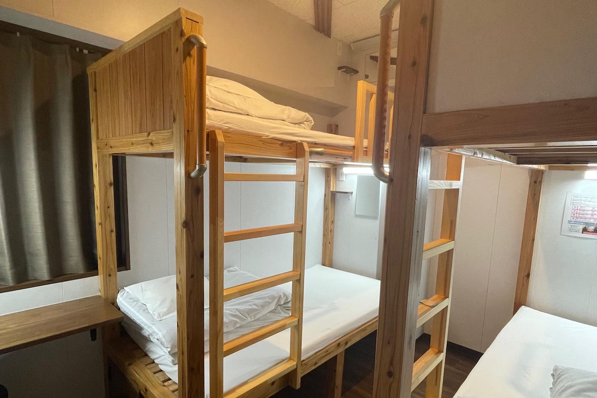 A bunk bed room with wooden frames and white bedding.