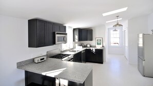 A modern kitchen with dark cabinets, a stainless steel refrigerator, and a central island. - Fabulous Cottage on Pristine Broad Bay (Waldoboro)