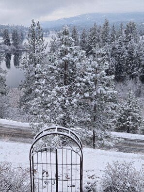 A metal gate in a snowy landscape with a lake and trees in the background. - Find a piece of Heaven at the Spirit of Curlew Lake (Republic)