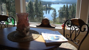 A table with a book, a vase, and a clock, overlooking a lake and forest. - Find a piece of Heaven at the Spirit of Curlew Lake (Republic)