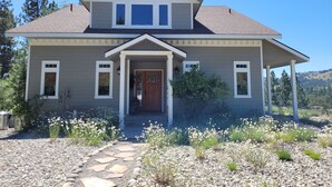 A two-story house with a front porch, a garage, and a landscaped garden with a stone pathway. - Find a piece of Heaven at the Spirit of Curlew Lake (Republic)