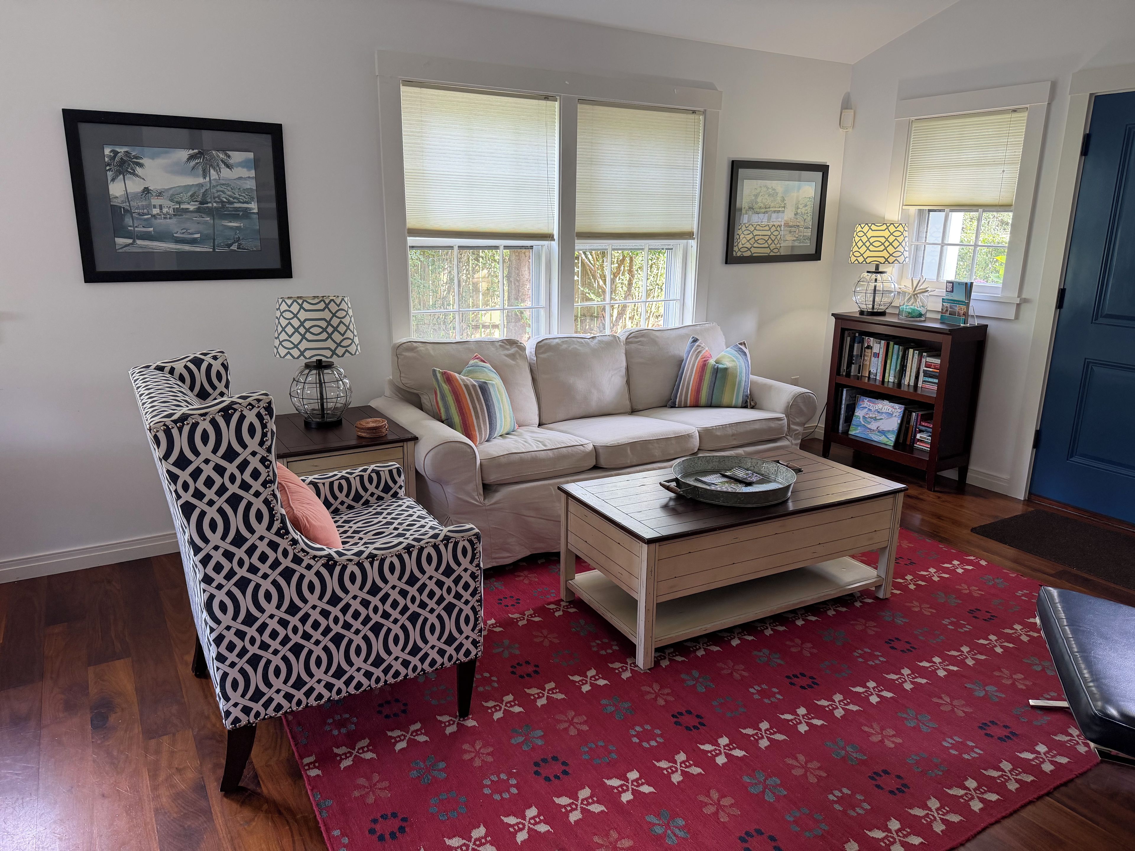 A living room with a sofa, armchair, coffee table, and a bookshelf.