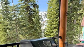 A portable grill on a wooden deck with a view of trees and a building in the background. - Deluxe Suite w/BBQ, Hot Tub, Laundry - Just minutes walking to village (Silver Star Mountain)