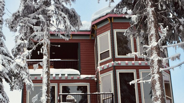 A multi-story building with a red exterior, large windows, and balconies. - Deluxe Suite w/BBQ, Hot Tub, Laundry - Just minutes walking to village (Silver Star Mountain)