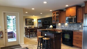 A kitchen with wooden cabinets, a stainless steel refrigerator, and a tiled backsplash. - Deluxe Suite w/BBQ, Hot Tub, Laundry - Just minutes walking to village (Silver Star Mountain)
