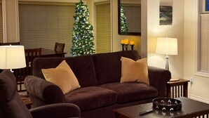 A living room with a brown sofa, a Christmas tree, and a lamp. - Deluxe Suite w/BBQ, Hot Tub, Laundry - Just minutes walking to village (Silver Star Mountain)