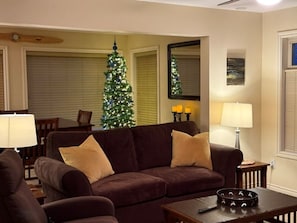 Un salon avec un canapé marron, un sapin de Noël et une lampe.