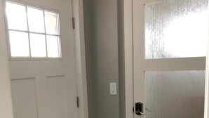 Un couloir avec deux portes blanches, dont l’une est dotée d’une fenêtre et l’autre de panneaux en verre dépoli.
