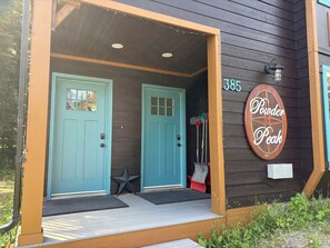 Una casa de madera con dos puertas turquesa, una decoración de estrella y un letrero que dice 'Powder Peak' con el número 385.