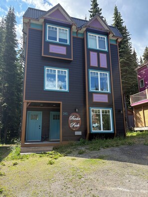 Un edificio de varios pisos con fachada oscura, múltiples ventanas y un letrero que dice 'Powder Peak'.