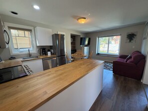 Una cocina moderna con una isla central, electrodomésticos de acero inoxidable y un comedor con televisor.