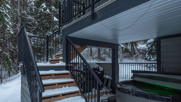 Un escalier en bois mène à une terrasse dotée d’un jacuzzi.