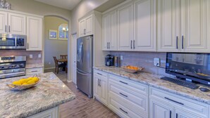 A modern kitchen with white cabinets, granite countertops, stainless steel appliances, and a built-in oven. - Golf Course & Mt VIEWS: Htd POOL, Hot Tub, Putting Green, Fire Pit, 3 Bikes (Mesa)
