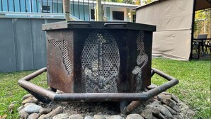 A metal structure with a decorative design, surrounded by rocks and grass, with a building and a tent in the background. - SASSA MERMAID WATERFRONT HOUSE WITH KAYAKS AND POOL (Homosassa)