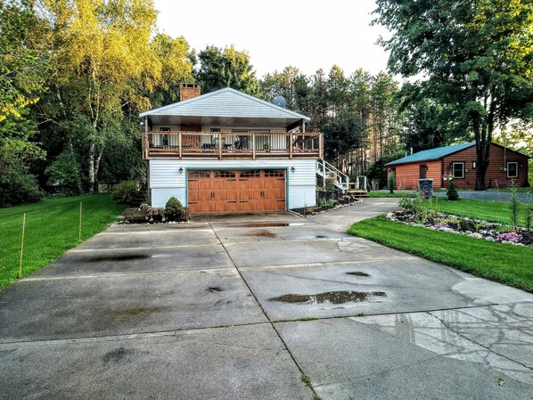 A two-story log cabin with a large garage and a balcony. - HOPE -Upper Silver Lake Vacation House close to Silver Lake Sand dunes (Mears)