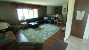A living room with a sectional sofa, a small table, a lamp, and a rug.